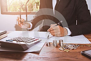 Businessman Writing paper and using calculator Calculating bonusOr other compensation to employees to increase productivity. on