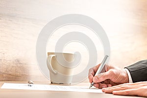 Businessman writing with a pen on a paper sheet