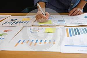 Businessman writing on sticky note on business document. paper r