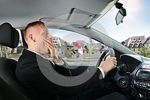 Businessman yawning while driving car