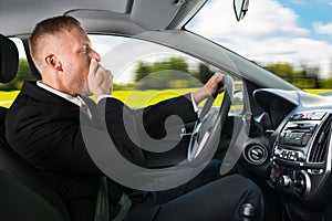 Businessman yawning while driving car