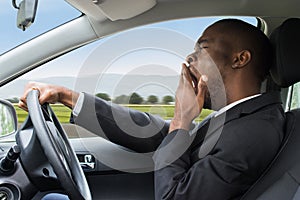 Businessman Yawning While Driving Car