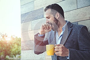 businessman yawning and holding coffee