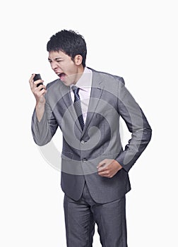 Businessman yelling at mobile phone, studio shot