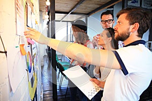 Businessman with young partners looking at whiteboard in creative office.