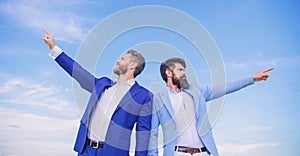 Businessmen bearded faces stand back to back sky background. Men formal suit managers pointing at opposite directions