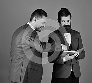 Businessmen with beards discuss business looking into notes. Machos in classic suits talk about schedule. Men with photo