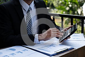 Businessmen bookkeeper hand holding pen and use calculator, laptop analysis the graph for Setting challenging business goals and