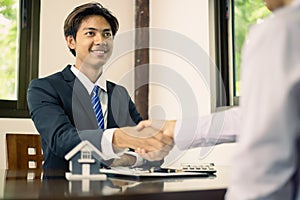 Businessmen and brokers real estate agents shake hands after completing negotiations to buy house insurance and sign contracts.