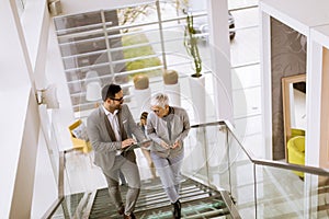 Businessmen and businesswomen walking and taking stairs in an of