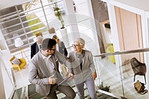 Businessmen and businesswomen walking and taking stairs in an of