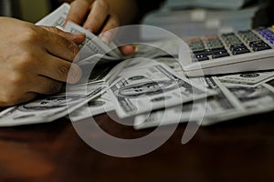 Businessmen counting money on a stack of 100 US dollars banknotes