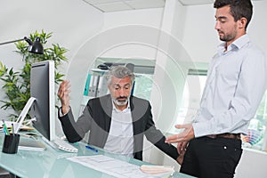 Businessmen debating when looking at laptop inoffice