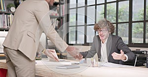 Businessmen from different ethnic and cultural backgrounds discuss the business idea. A man with a brown hair is debating