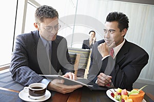 Businessmen Discussing Contract In Restaurant