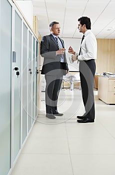 Businessmen Discussing In Office Corridor