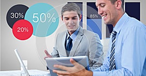 Businessmen discussing over tablet PC by graphs