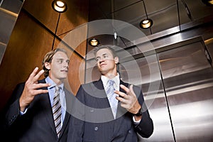 Businessmen in elevator conversing