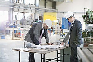 Businessmen examining blueprint at workbench in metal industry