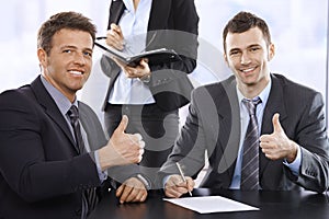 Businessmen giving the thumbs up, smiling