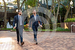 Businessmen go to work. Business taliking. Two businessmen in elegant business suits, walking and talking in city street