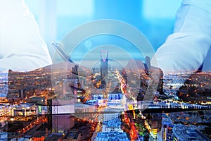 Businessmen hands signing documents on Riyadh skyline city scape background