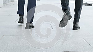 Businessmen legs walking on urban street together. Colleagues going for work