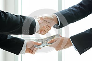 Businessmen making handshake while passing money