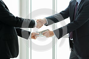 Businessmen making handshake while passing money