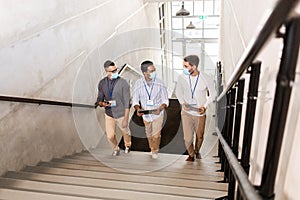 businessmen in masks with name tags going upstairs