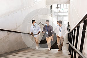 businessmen in masks with name tags going upstairs