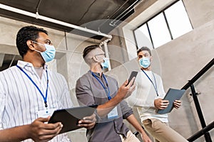 businessmen in masks with name tags going upstairs