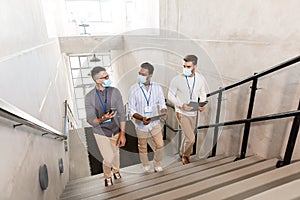 businessmen in masks with name tags going upstairs