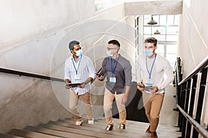 businessmen in masks with name tags going upstairs