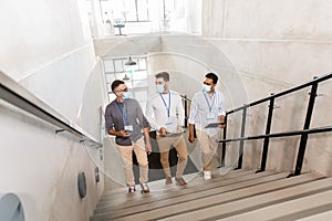 businessmen in masks with name tags going upstairs