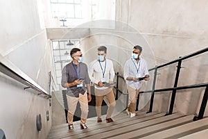 businessmen in masks with name tags going upstairs