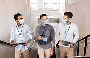 businessmen in masks with name tags going upstairs