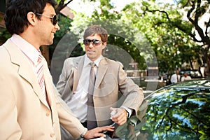 Businessmen meeting around car.