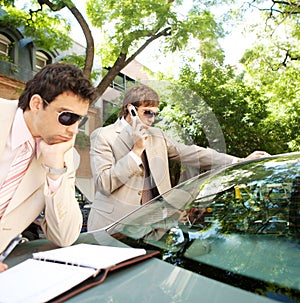 Businessmen meeting around car.