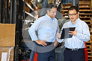 Businessmen Meeting By Fork Lift Truck In Warehouse