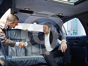 Businessmen Meeting In Limousine And Shaking Hands