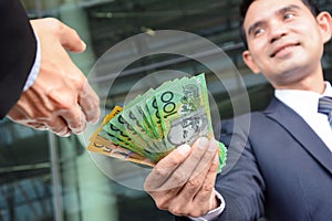 Businessmen passing money, Australia dollar banknotes