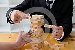 Businessmen picking wood blocks to fill the missing wood blocks and protect wood blocks to fail. Growing business concept