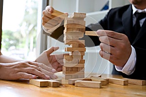 Businessmen picking wood blocks to fill the missing wood blocks and protect wood blocks to fail. Growing business concept