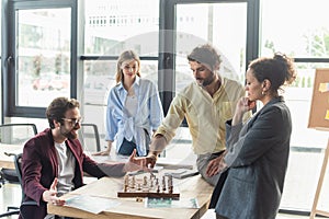 Businessmen playing chess near interracial colleagues