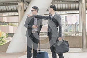 Businessmen pointing the way to stranger man who was meet on the street.Young businessman wearing a suit and sunglasses with