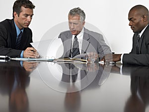 Businessmen Reading Documents In Conference Room