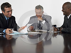 Businessmen Reading Documents In Conference Room