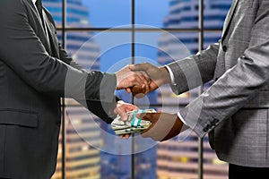 Businessmen's handshake and money transfer.