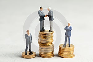 Businessmen shake hands as a symbol of a successful profitable transaction. Businessmen on a stack of gold coins as a symbol of